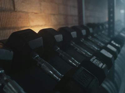 Dumbbells lined up against a wall in a sunlight gym